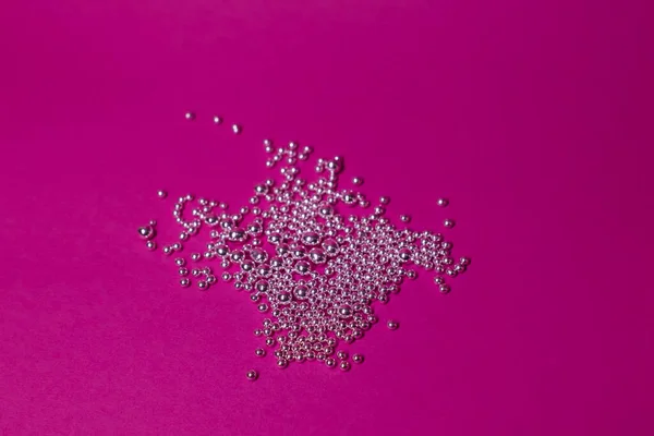 Un montón de bolitas de plata sobre un fondo rosa. Abstracto —  Fotos de Stock