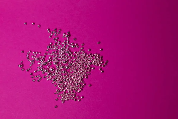 Un montón de bolitas de plata sobre un fondo rosa. Abstracto —  Fotos de Stock