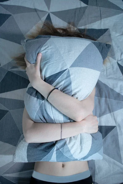 Štíhlá dívka v posteli se přikrývá polštářem — Stock fotografie