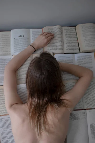 Chica delgada semidesnuda se encuentra en los libros abiertos - la lectura. estudio en casa —  Fotos de Stock