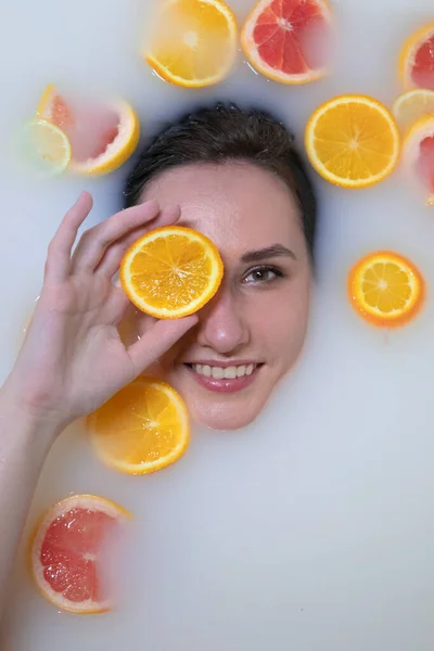 우유 목욕에 오렌지, 레몬,그 레이프프 프루트를 곁들인 여성 사진. 패션 모델, 스파 및 피부 관리 개념. — 스톡 사진