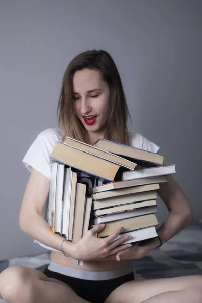 Dziewczyna trzyma w rękach wiele różnych książek. Nauka w domu. Czytanie jest pomocne — Zdjęcie stockowe