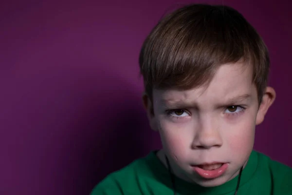 Retrato de um menino loiro de nove anos com raiva pensativa em um fundo rosa — Fotografia de Stock