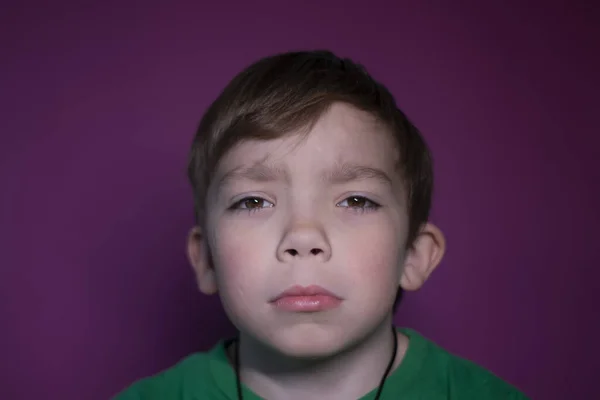 Retrato de um triste menino loiro de nove anos de idade em um fundo rosa — Fotografia de Stock