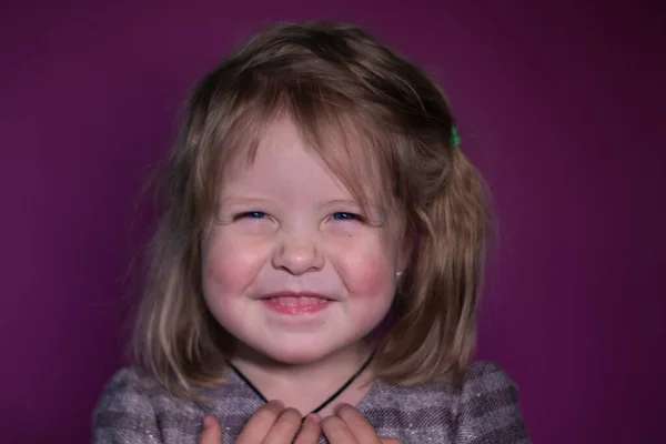 Portret van gelukkig een drie jaar oud blond meisje met blauwe ogen op een roze achtergrond — Stockfoto