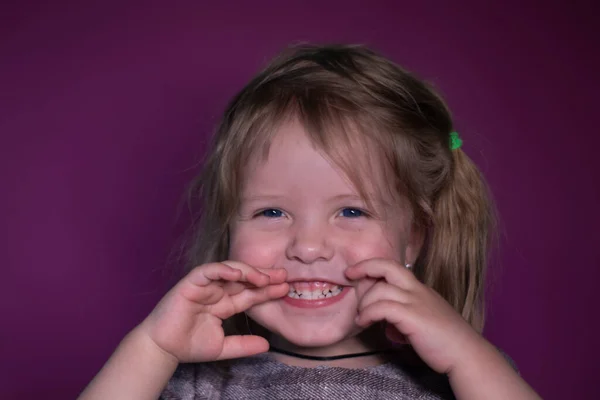 Retrato de feliz uma menina loira de três anos de idade com olhos azuis em um fundo rosa — Fotografia de Stock