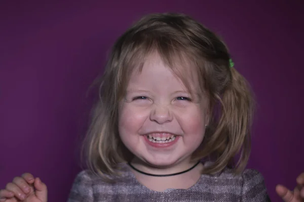 Retrato de feliz una niña rubia de tres años con ojos azules sobre un fondo rosa —  Fotos de Stock