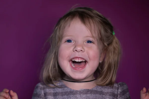 Retrato de feliz una niña rubia de tres años con ojos azules sobre un fondo rosa —  Fotos de Stock