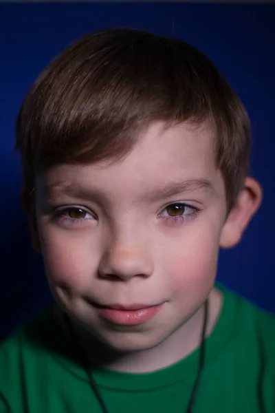 Portrait d'un garçon blond heureux et paisible de neuf ans souriant sur un fond bleu — Photo