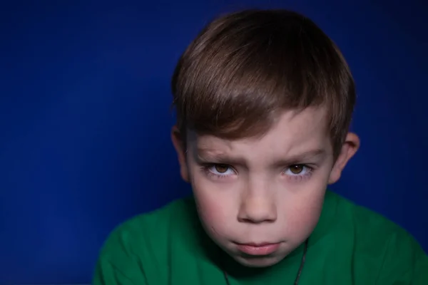 Retrato de um triste menino loiro de nove anos pensivo em um fundo azul — Fotografia de Stock