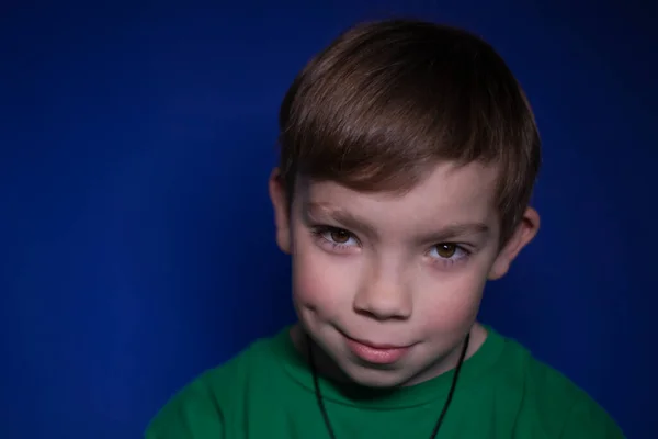 Portret van een negen jaar oude blonde jongen op een blauwe achtergrond — Stockfoto