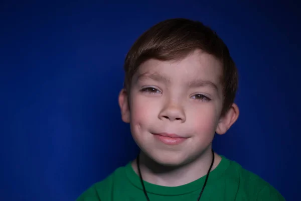 Retrato de un niño rubio feliz y tranquilo de nueve años sonriendo sobre un fondo azul —  Fotos de Stock