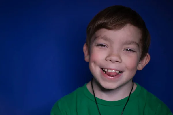 Portret van een gelukkige vreedzame negen jaar oude blonde jongen glimlachen op een blauwe achtergrond — Stockfoto