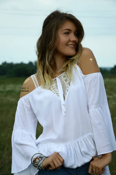 Retrato de una mujer hermosa coqueta feliz en blusa blanca en el campo. Tatuaje temporal. Dibujos en el cuerpo. hippie. Naturaleza amorosa . —  Fotos de Stock