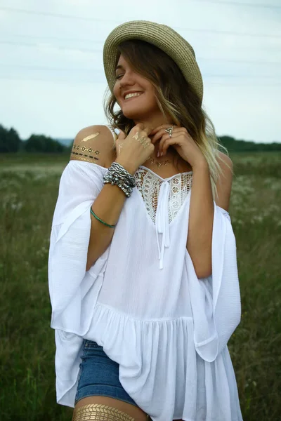 Retrato de uma mulher bonita sedutora feliz em blusa branca e chapéu de palha no campo. Tatuagem temporária. Desenhos no corpo. Hippie. Natureza amorosa . — Fotografia de Stock