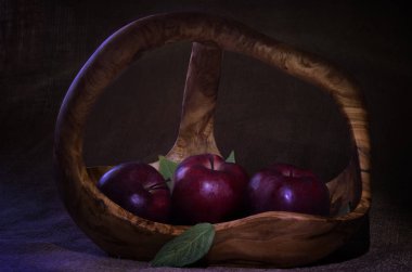 Tahta sepette birkaç yeşil yapraklı kırmızı elmalar.