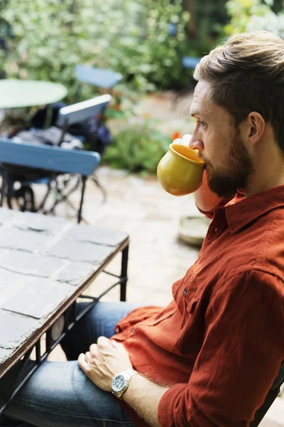 Ο άνθρωπος που πίνει καφέ στο τραπέζι στο θερμοκήπιο — Φωτογραφία Αρχείου