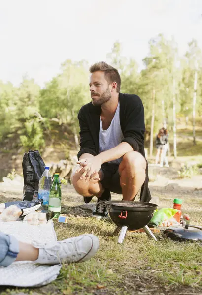 Muž sedě schoulen u grilu — Stock fotografie