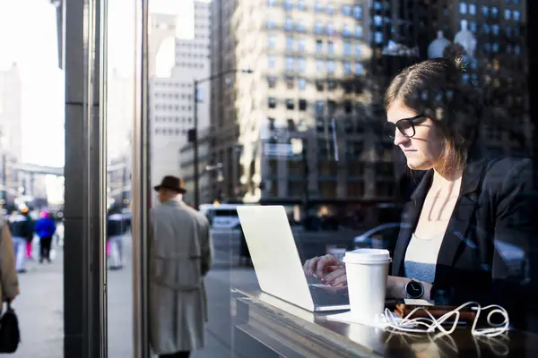 Mujer de negocios usando el ordenador portátil mientras está sentado en la cafetería — Foto de Stock