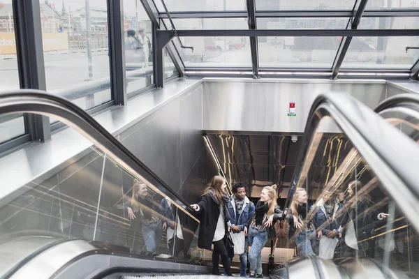 Amigos subindo na escada rolante no edifício de vidro — Fotografia de Stock
