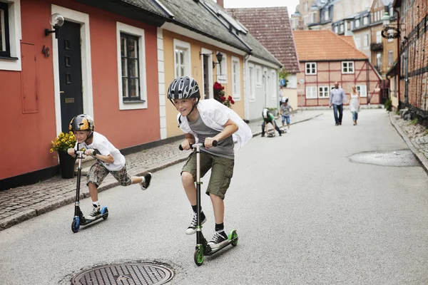 Jongens die duw scooters rijden — Stockfoto