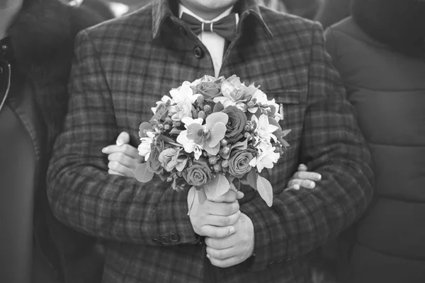 Noivo elegante com buquê de rosas nas mãos, dia do casamento, vista de close-up, tonificação preto e branco — Fotografia de Stock