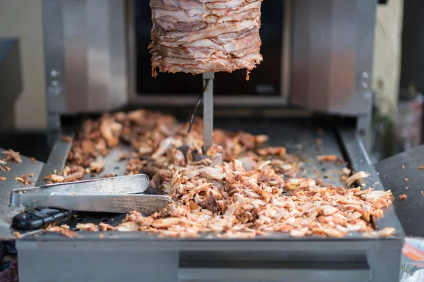 Gerät zum Kochen von Shawarma, Fleischschichten am Spieß aufgereiht, Hackfleisch auf Grillfläche, Zange und Messer, Frontansicht — Stockfoto