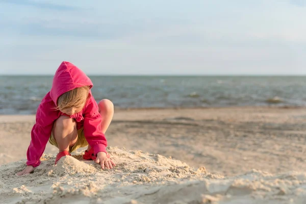 Niña de tres años jugando en la arena en la playa del mar, puesta de sol y poca brisa y, vacaciones de verano, desarrollo infantil, mejora de la salud —  Fotos de Stock