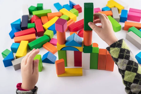 Четырехлетняя девочка играет в дизайнере. Деревянные игрушки, красочный детский дизайнер на белом фоне, развлечения с ребенком, развитие дошкольников, строительство — стоковое фото
