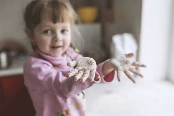 Malá holčička hraje v kuchyni, ruce v mouce — Stock fotografie