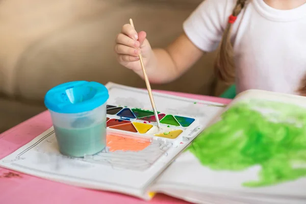 Little girl coloring drawings sitting at the table, child development