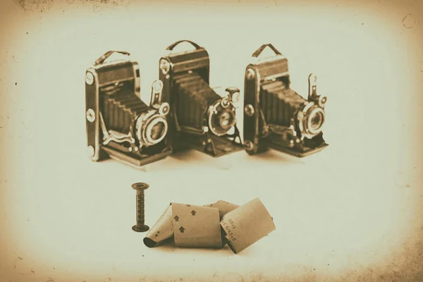 Film 120 pour appareils photo rétro de format moyen sur fond blanc avec ombres, caméras vintage floues sur fond, effet antique — Photo