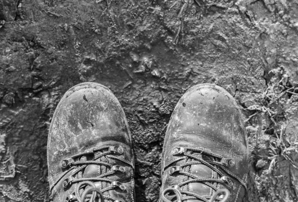 As botas estão sujas com pântano, na estrada de terra, vista superior. Tom monocromático — Fotografia de Stock