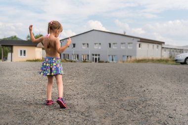 Beş yaşında beyaz bir kız sıcak bir yaz gününde bahçede eğleniyor, bahçede dans ediyor ve hayatın tadını çıkarıyor.