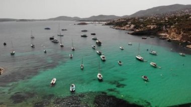 Yazın körfezdeki turkuaz deniz suyunda yatlar. Playa de Illetas plajındaki Punta des Bufador, Mayorka 'da güzel ve popüler bir turizm merkezidir. Hava aracı 4K. Sinema görüntüsü.