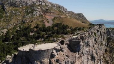 Kudretli kayanın hava aracı görüntüsü, etrafından dön. Mirador Es Colomer 'deki turistler, aynı zamanda rüzgarların buluşma noktası olarak da bilinir. İspanya 'nın Mayorka Adası' nda popüler ve manzaralı bir turizm beldesi.