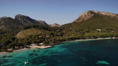 Platja de Formentor sahilinin turkuaz deniz suyuyla kuşbakışı görüntüsü. İnsanlar plajda dinleniyor. Mallorca 'da güzel, egzotik ve popüler bir turizm merkezi. Hava Aracı 4K, pan