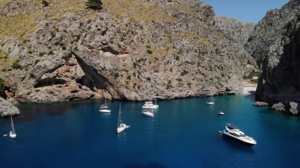 游艇在蔚蓝的海水中 在雄伟的石山之间 世界上的天堂美丽的大自然在小港口村Sa Calobra 马约卡岛受欢迎的异国情调旅游胜地 无人机4K — 图库视频影像