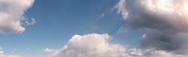Sıcak, güneşli tonlarda mavi bulutlu bir arka plan. Geniş açılı panoramik doğal arkaplan, pankart biçimi.
