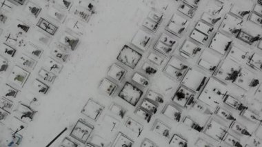 Birçok mezarı olan bir hava aracıyla mezarlığın görüntüsü. İnsanlar, ölen akrabalarının ruhlarının huzura ermesi için dua etmeye mezarlara gelirler. Noel arifesinden önce. Ukrayna 'da din ve Hıristiyan gelenekleri. Yukarıdan vinç atışı.