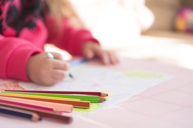 Masada duran renkli kalemler. Küçük bir çocuğun çizim süreci, yakın görüş. Kopyalama alanı olan yumuşak arkaplan. Çocuk gelişimi, eğlence ve hobi konuları.