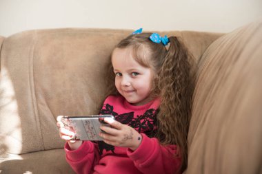 Drohobych, Ukrayna - 16 Nisan 2020: Güzel çocuk gülümsüyor ve cep telefonunu elinde tutuyor