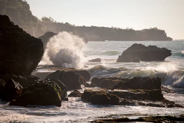 Ondas oceânicas colidindo com as rochas ao pôr do sol — Fotografia de Stock