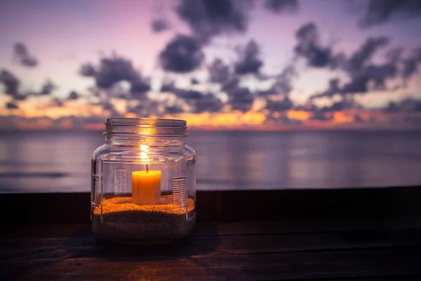 Свечная лампа на столе на фоне моря и заката — стоковое фото