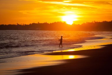 Mutlu genç balıkçı çocuk gün batımında sahilde