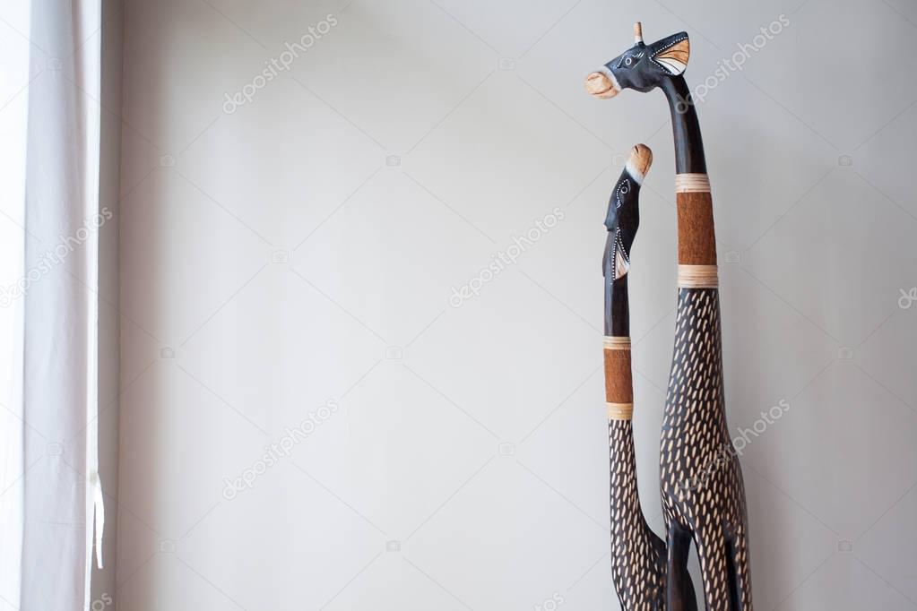 Scrimshaw giraffes from the tree in front of a white wall