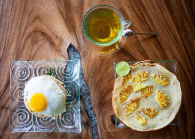 Geleneksel Asya Kahvaltı, yumurta, pirinç gözleme ananas ve ahşap masa üzerinde çay