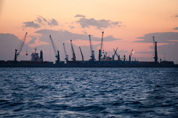 Námořní nákladní přístav s jeřáby při západu slunce — Stock fotografie