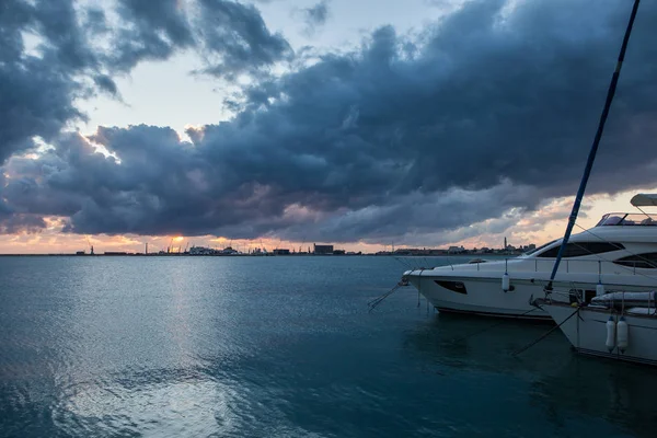 Zonsopgang boven de zee met dreigende wolken in de achtergrond van de commerciële haven — Stockfoto