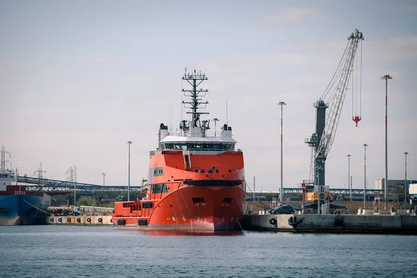 Rotes Frachtschiff vor Hafenanlagen und Kränen — Stockfoto